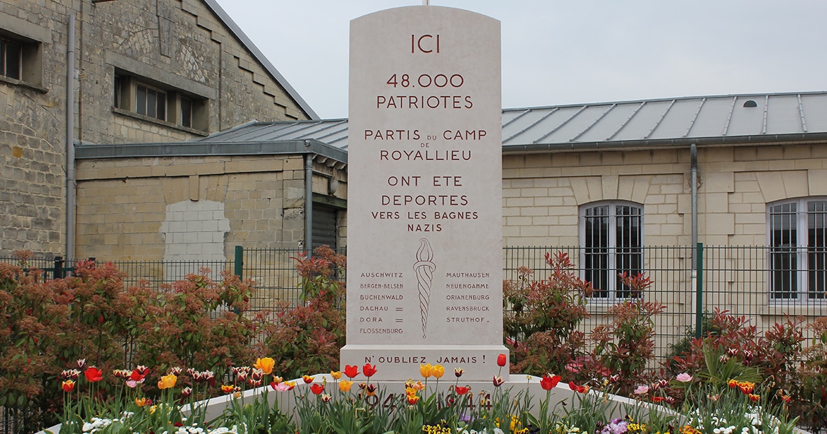 Pierre commémorative au camp de Royallieu, près de l'Hébergement Compiègne, France, entourée de fleurs, commémorant 48 000 patriotes déportés dans les camps nazis pendant la Seconde Guerre mondiale.